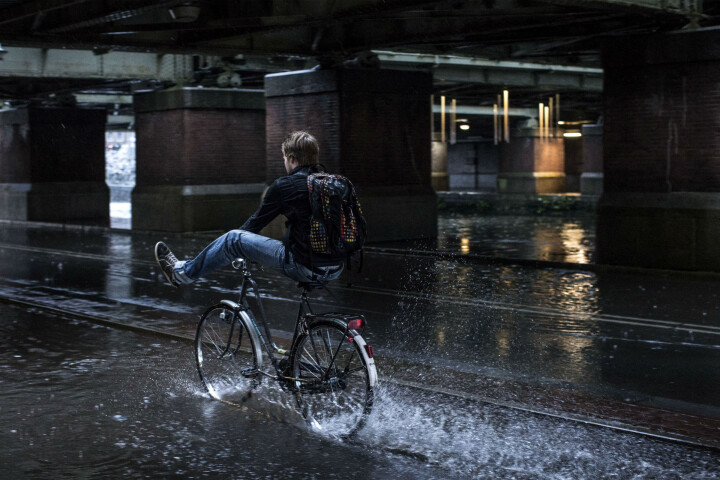 Jongen die door een plas water fietst